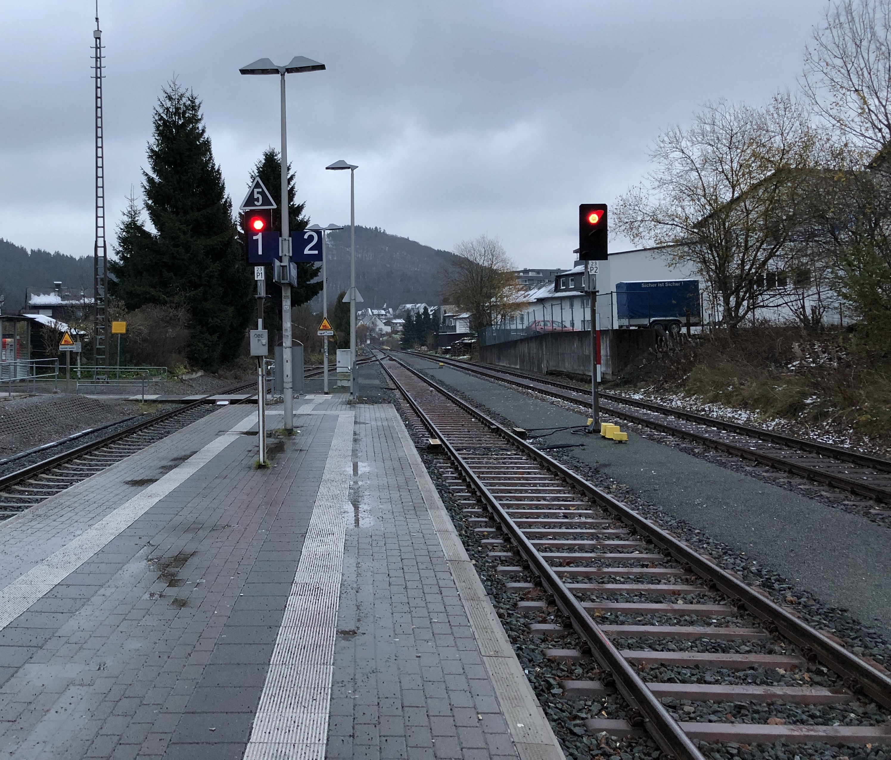 Photo of a train track in a station, with a red traffic light indicating all stop, and a change of direction for Baldi.